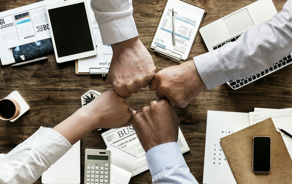 Team Work 4 office members fist bumping at a meeting